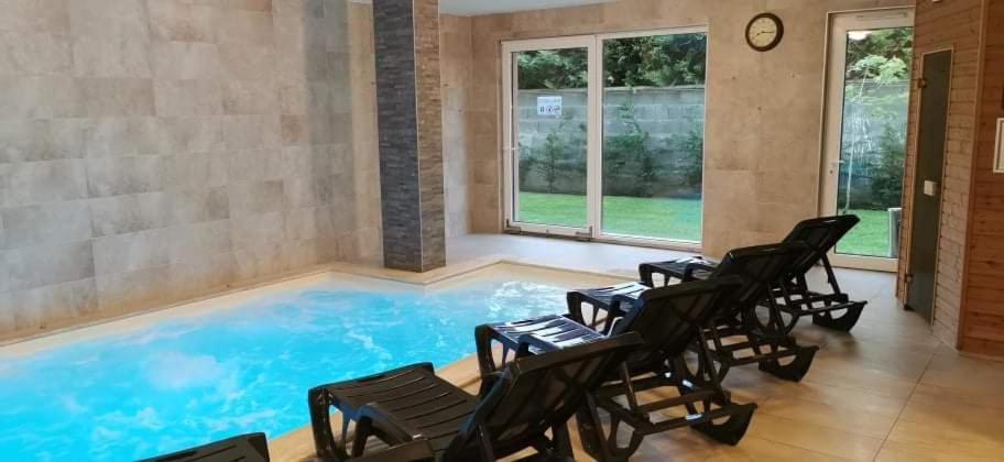 a large swimming pool with chairs and windows at Syrah Wellness Apartman Siófok in Siófok