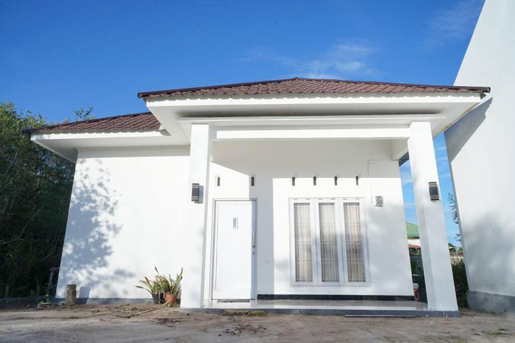 uma pequena casa branca com um telhado vermelho em Rumah Kita em Palangkaraya