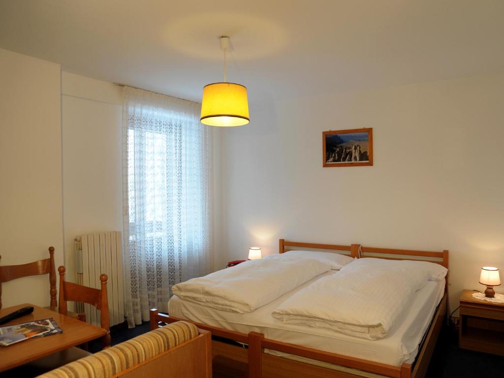 A bed or beds in a room at Hotel Pensione Dolomiti