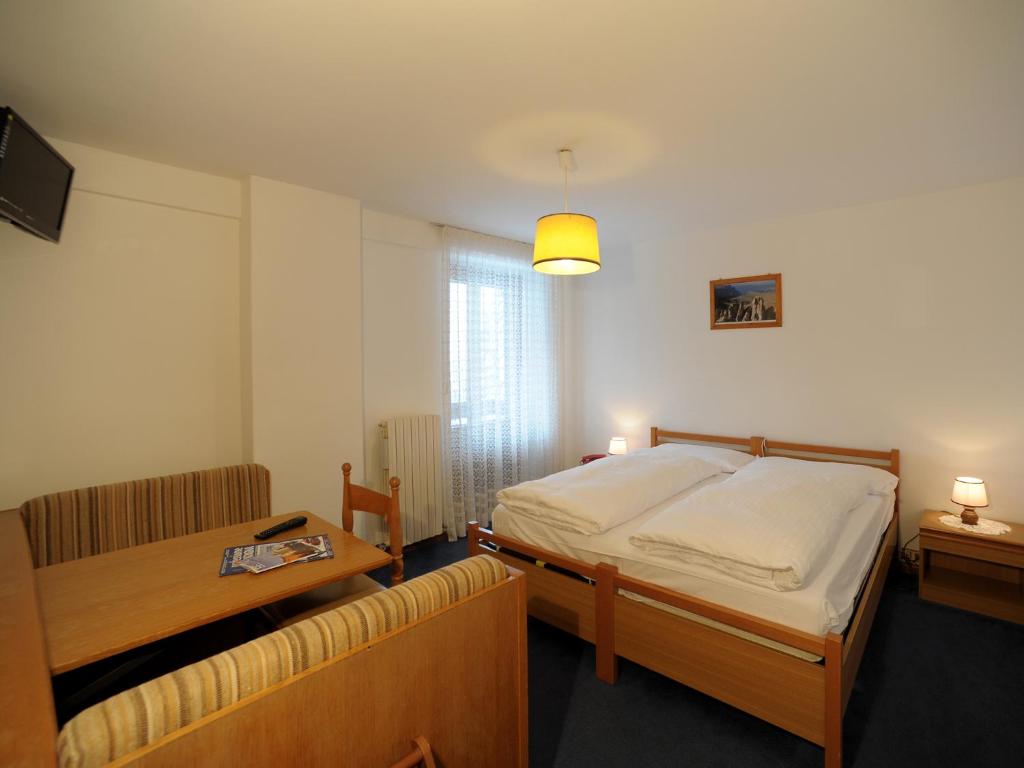 A bed or beds in a room at Hotel Pensione Dolomiti