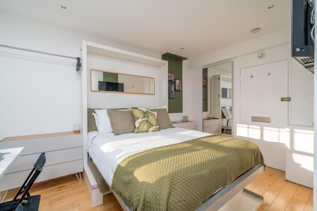 a bedroom with a bed and a desk and a window at Chelsea, London - Lovely Studio Apartment in London