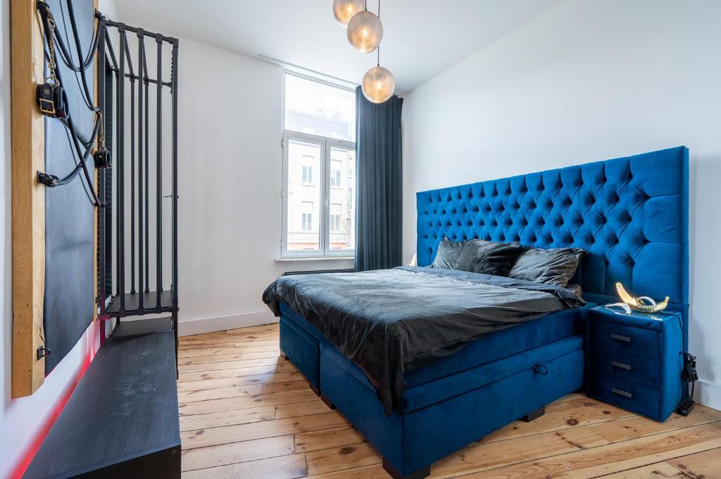 a bedroom with a blue bed with a blue headboard at The Rabbit Hole Antwerp - Romantic apartment with adult playroom in Antwerp