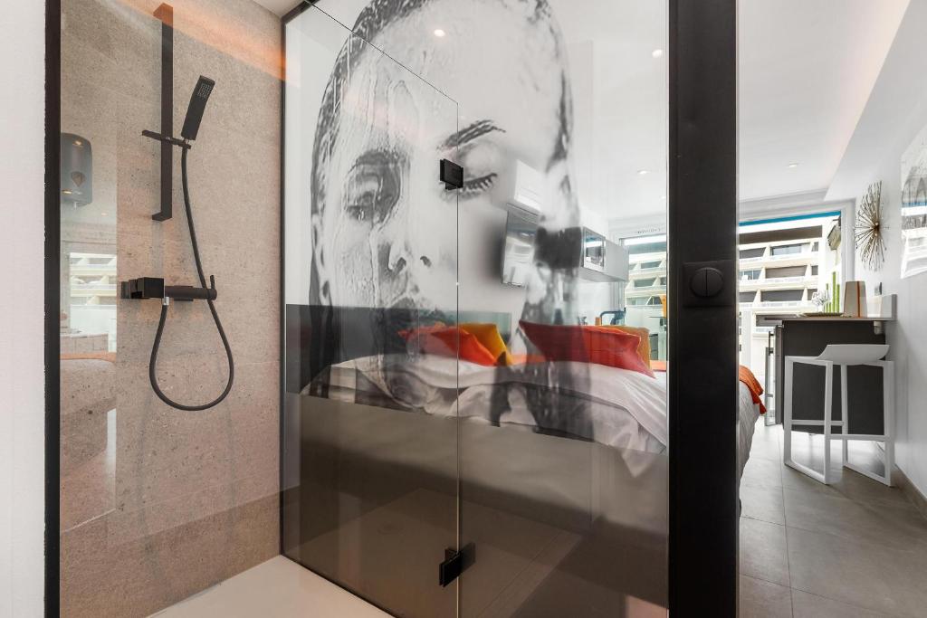 a bathroom with a shower with a painting of a woman at Village Naturiste R4N - Le Xillion Port Nature in Cap d'Agde