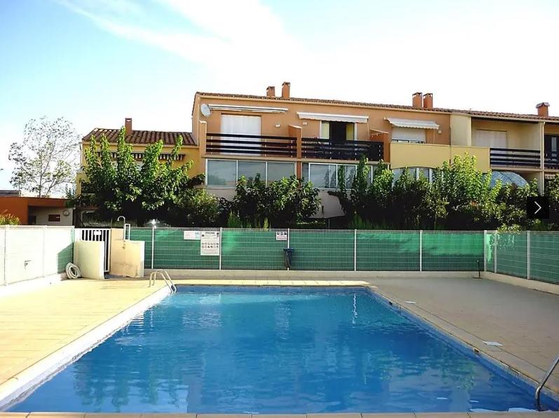 une grande piscine bleue devant un immeuble dans l'établissement 5018 Estivales 11G, au Cap d'Agde