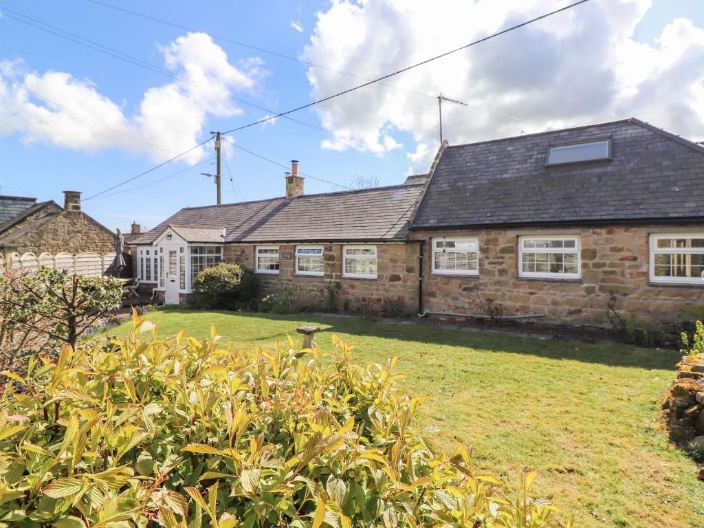 a brick house with a yard in front of it at West Farm Cottage in Morpeth