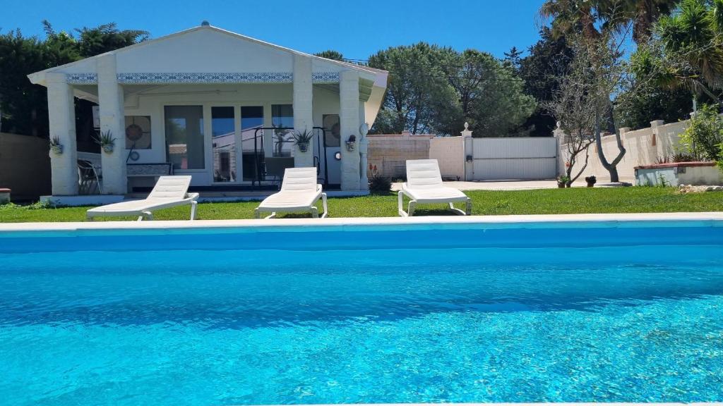 a house with two chairs and a swimming pool at Casa Poniente in Chiclana de la Frontera