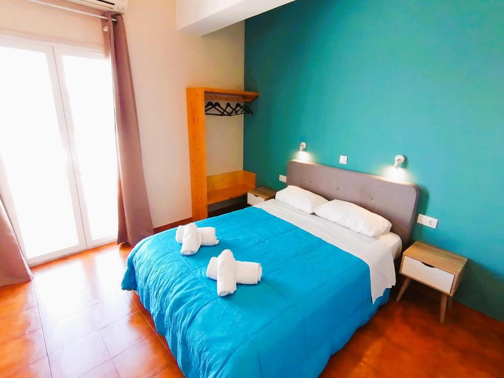 a bedroom with a blue bed with towels on it at Perdika Mare Guesthouse in Perdhika