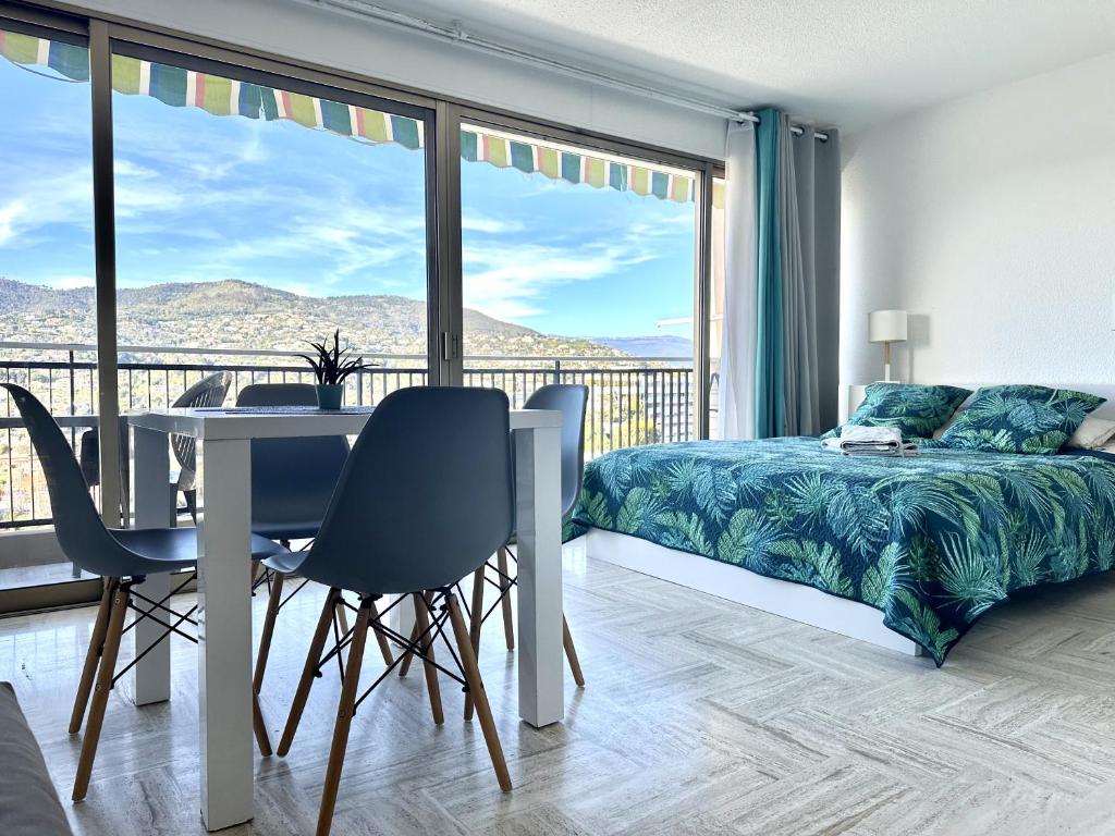Schlafzimmer mit einem Bett und einem Tisch sowie einem Balkon in der Unterkunft vue marina et vue montagne in Mandelieu-la-Napoule