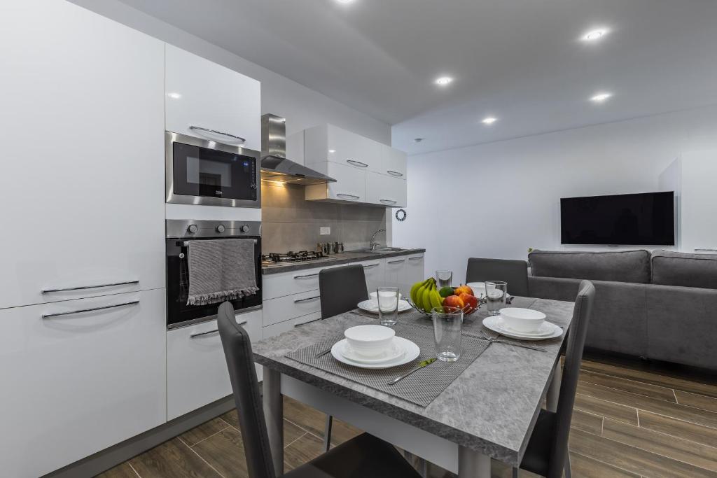 a white kitchen with a table and a couch at Sandstone A8 Marsascala - 15minute drive to Valletta in Marsaskala