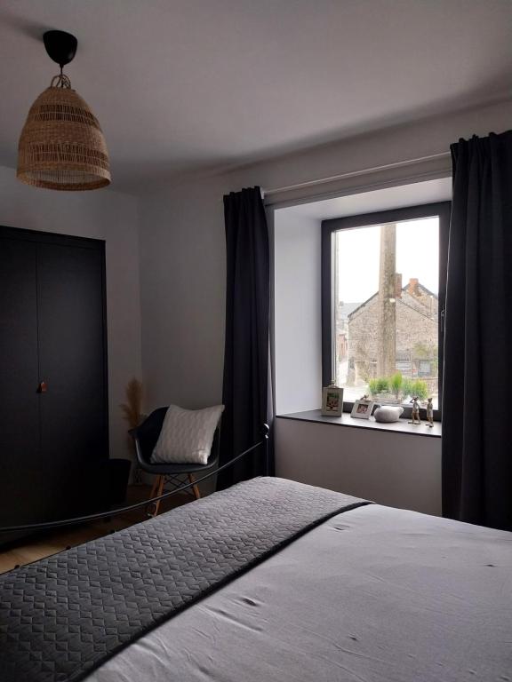 Au Cœur des Vallées في كوفين: غرفة نوم بسرير ونافذة بها كرسي