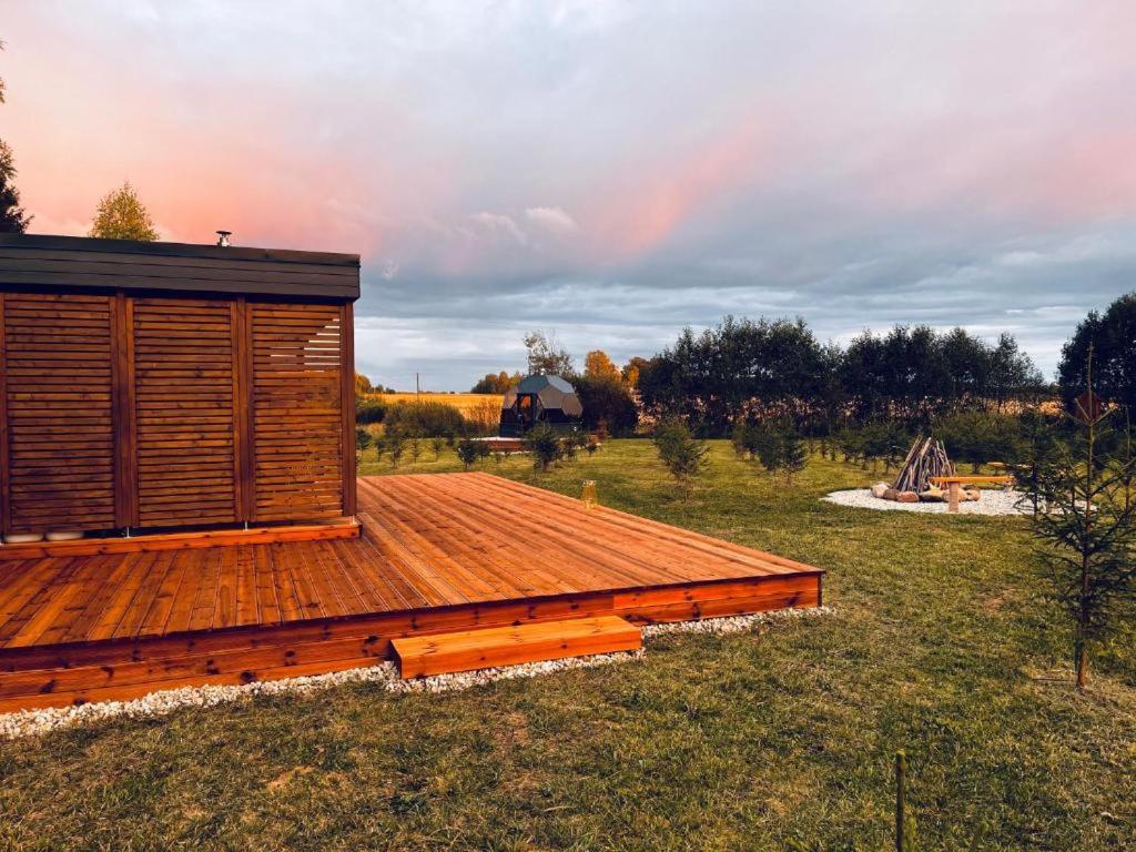 a wooden cabin in a field with a rainbow in the sky at Kuuselepa klaaskuppel in Tartu