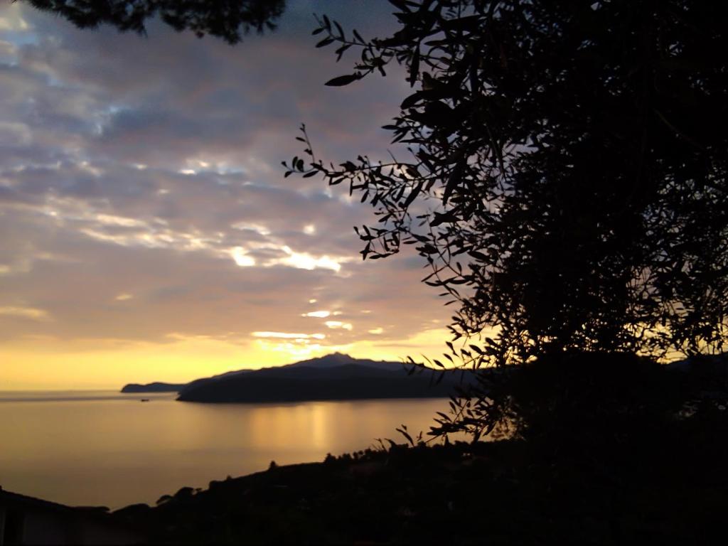 una puesta de sol sobre un cuerpo de agua con una montaña en La casa dei nonni, en Capoliveri