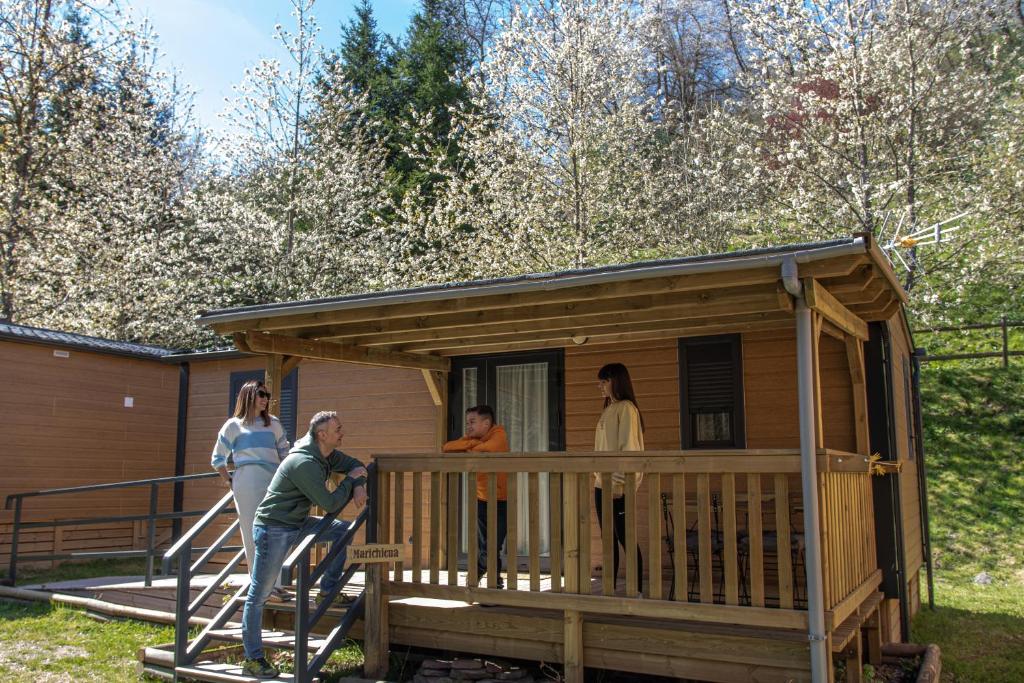 eine Gruppe von Menschen, die auf der Veranda eines winzigen Hauses stehen in der Unterkunft CAMPING RESORT LA TRAPERA in Pradoluengo