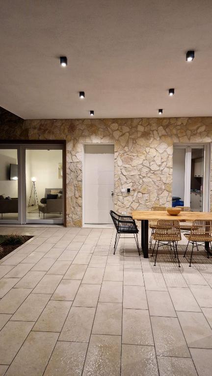 un patio avec une table et des chaises et un mur en pierre dans l'établissement Villa My Lagozise, à Pacengo di Lazise