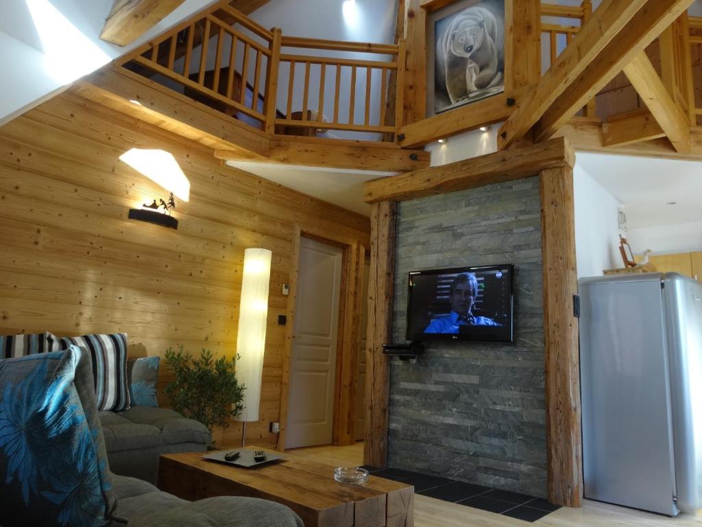 a living room with a couch and a tv on a wall at Les Terrasses des Glaciers - Appartement 2 in Chamonix