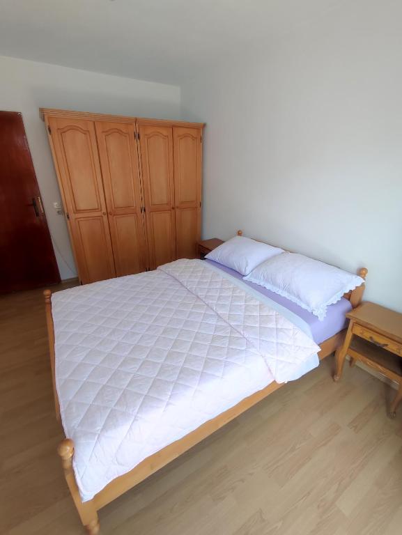 a bedroom with a bed and a wooden cabinet at Apartman Bor s velikom terasom idealan za boravak s obitelji in Livno