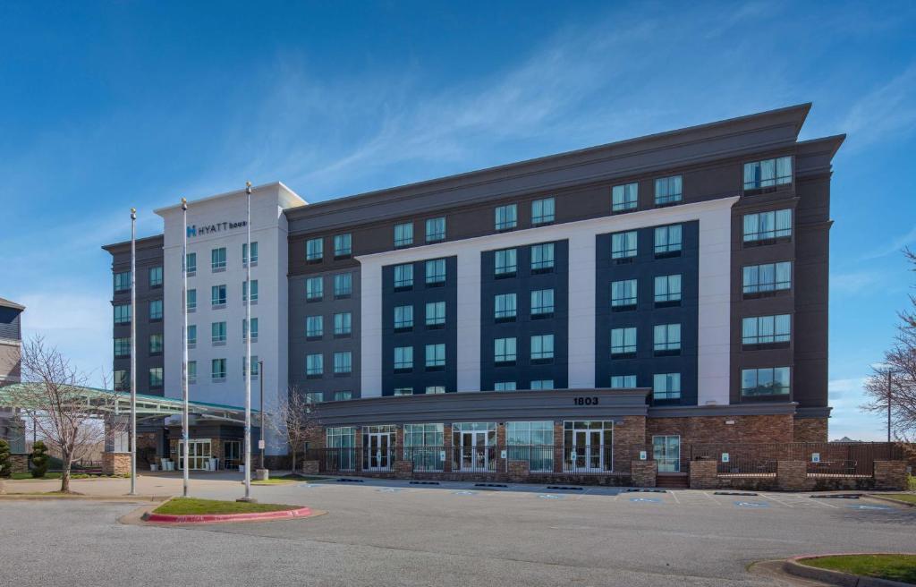 a large building with a parking lot in front of it at Hyatt House Bentonville Rogers in Rogers