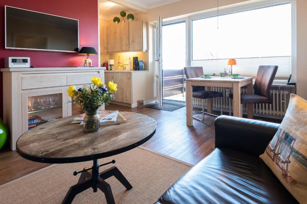 ein Wohnzimmer mit einem Sofa und einem Tisch mit Blumen in der Unterkunft Syltdomizil Westsuite in Wenningstedt-Braderup
