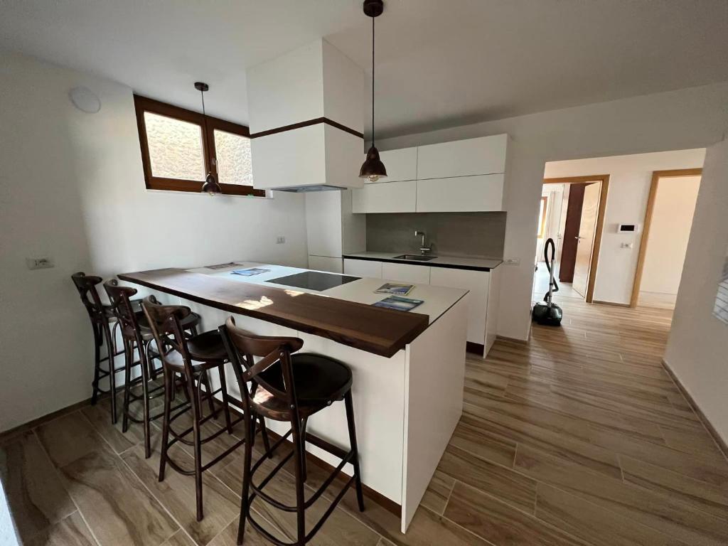 a kitchen with white cabinets and a island with bar stools at Kalaja Apartment in Prizren