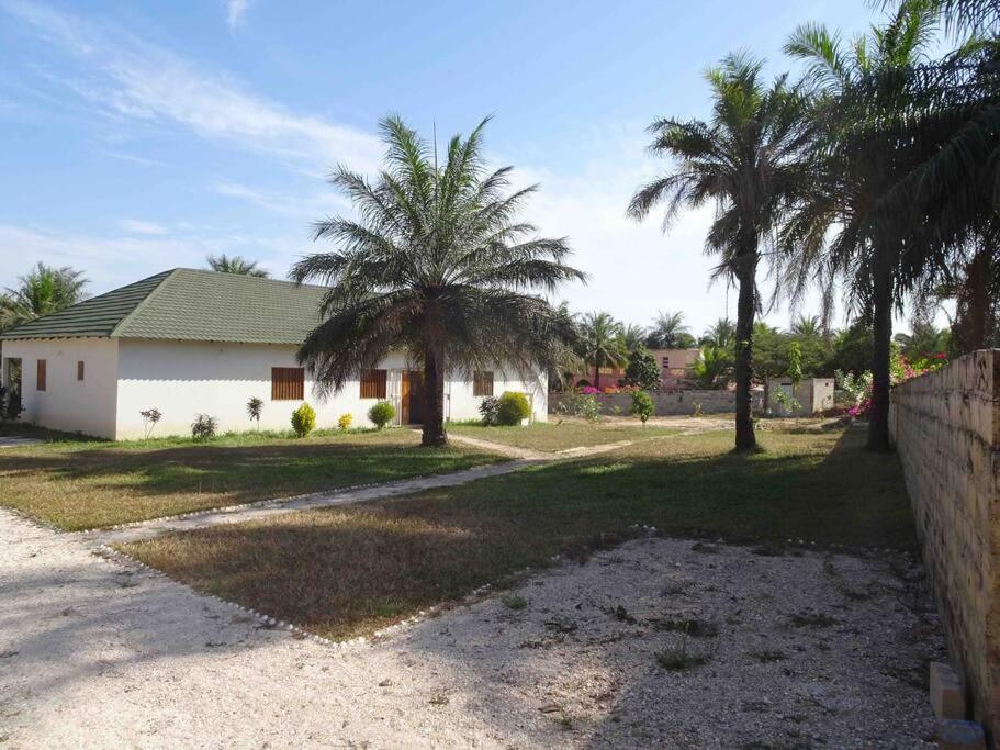 a house with palm trees in front of it at La Mangrove Villa paisible dans un cadre luxuriant in Cap Skirring