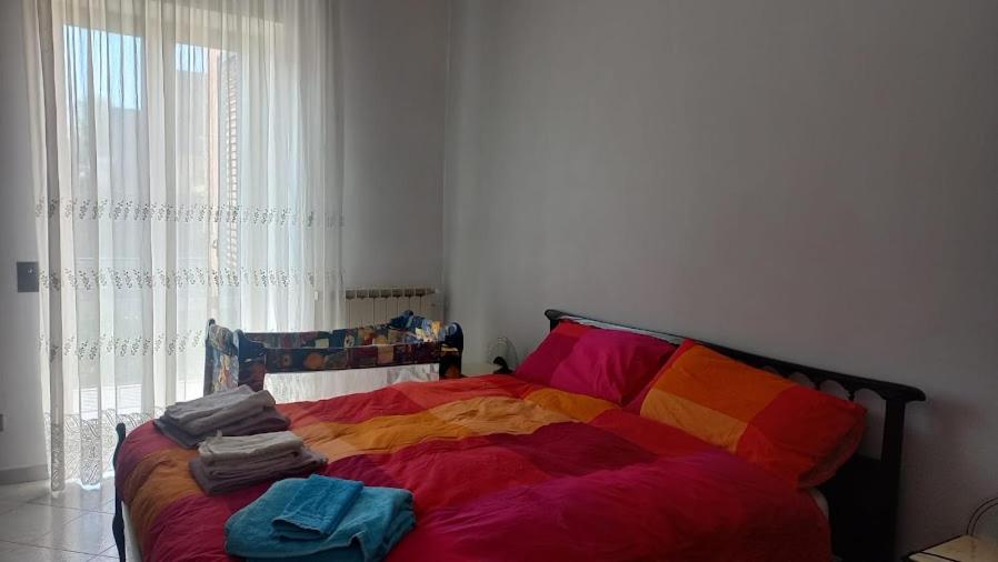 um quarto com uma cama com lençóis coloridos e uma janela em La Casa Dei Nonni em Nápoles