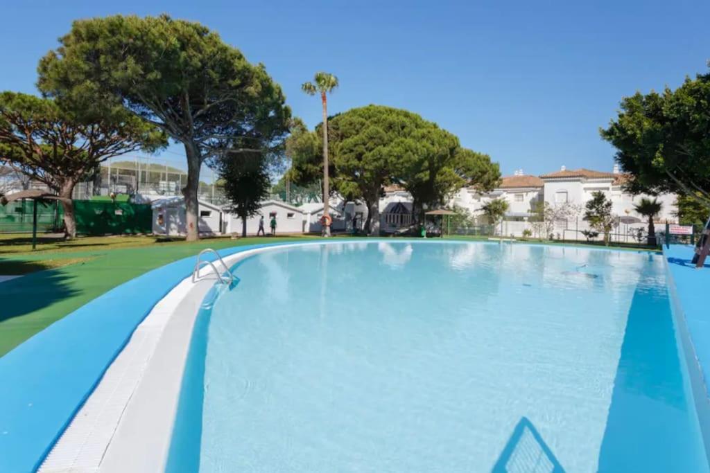 una gran piscina en un parque con árboles en Amplio apartamento en La Barrosa, en Novo Sancti Petri