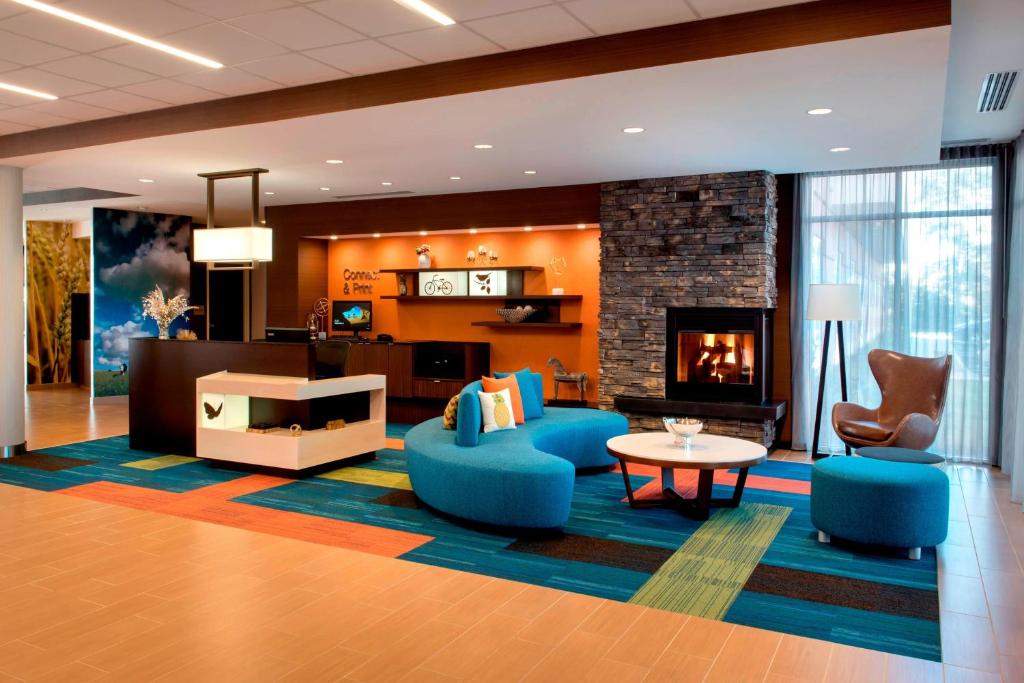 a living room with a fireplace and blue chairs at Fairfield Inn & Suites by Marriott Buffalo Amherst/University in Amherst