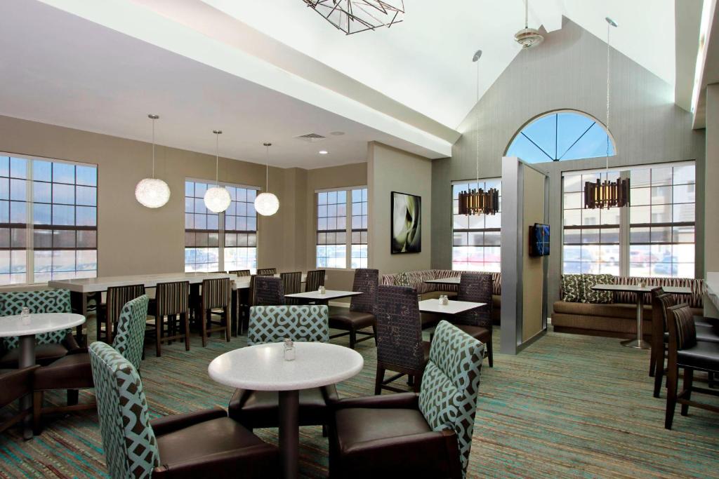 un comedor con mesas, sillas y ventanas en Residence Inn Colorado Springs South en Colorado Springs