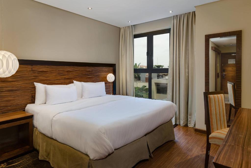 um quarto de hotel com uma cama grande e uma secretária em Protea Hotel by Marriott Ikeja Select em Ikeja