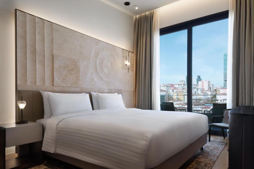 Marriott Executive Apartments Istanbul Fulya في إسطنبول: غرفة نوم بسرير ابيض ونافذة كبيرة