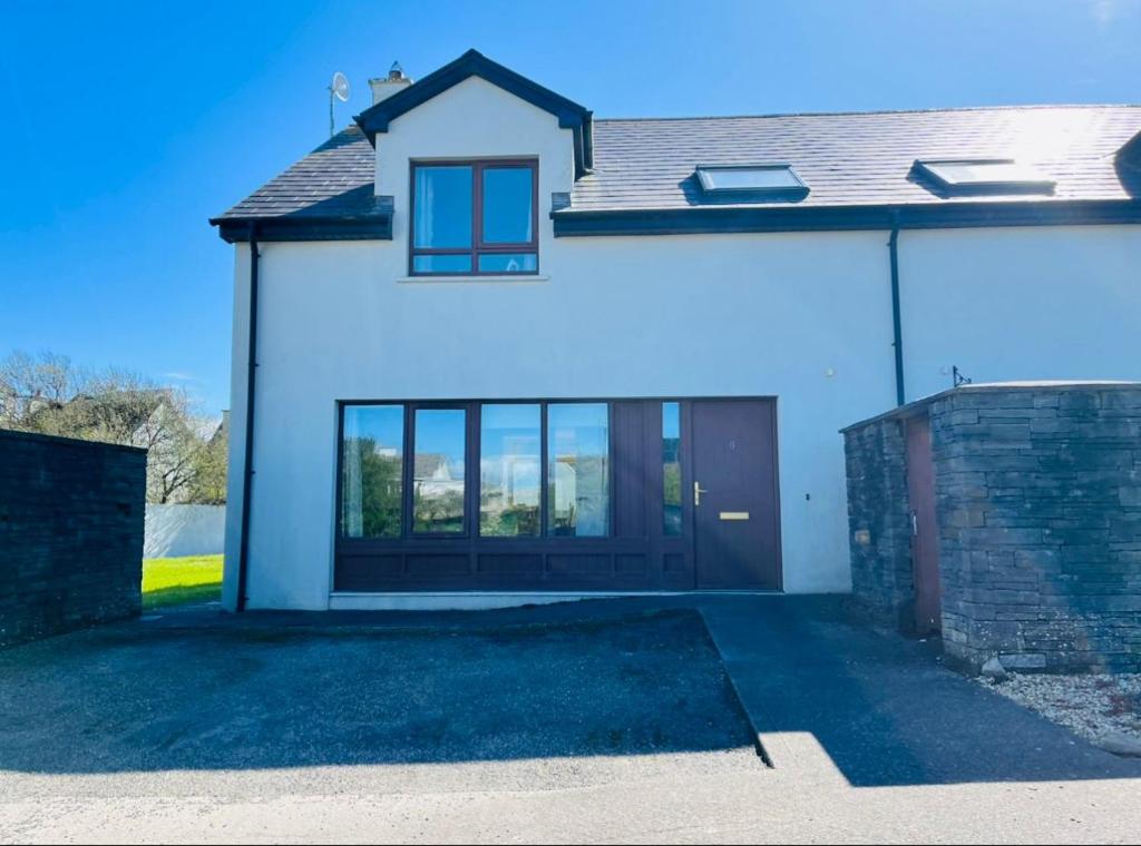 a white house with a brown door and windows at No. 6 Corran Meabh in Lahinch