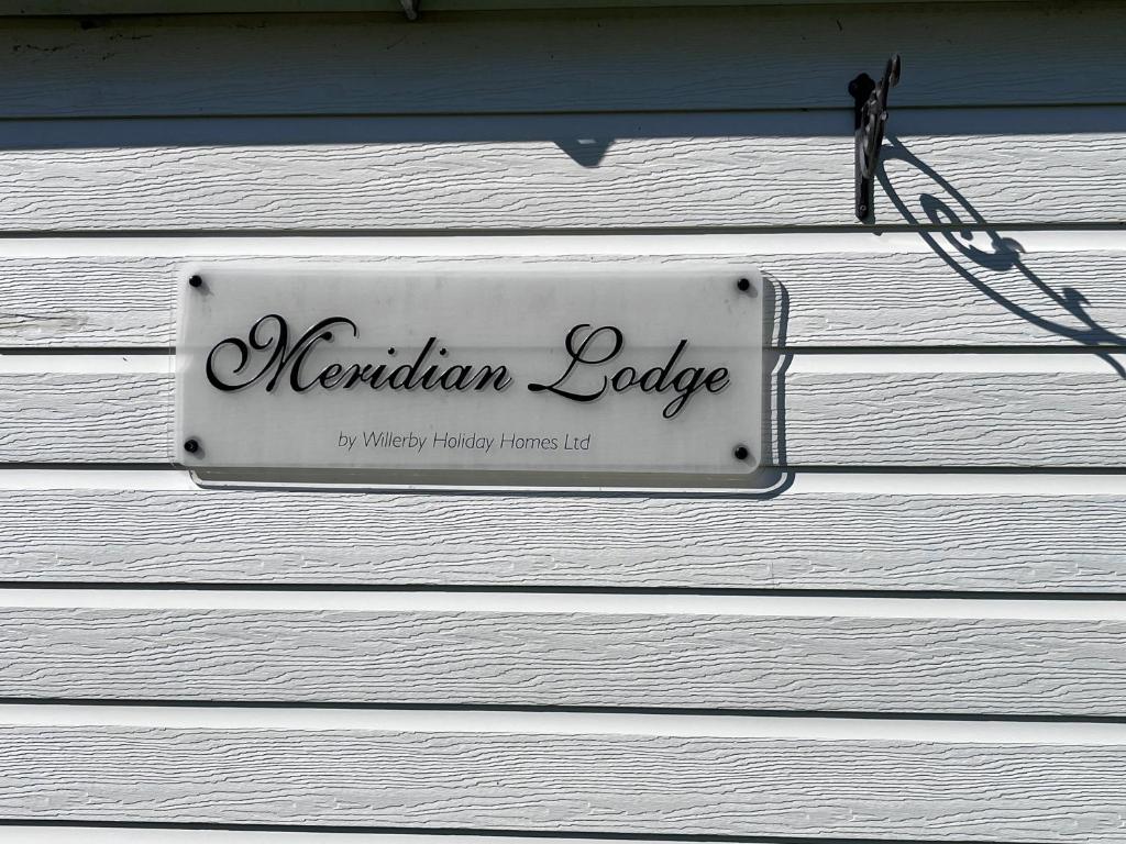 una señal en el lado de una casa blanca en Meridian Lodge en Great Billing