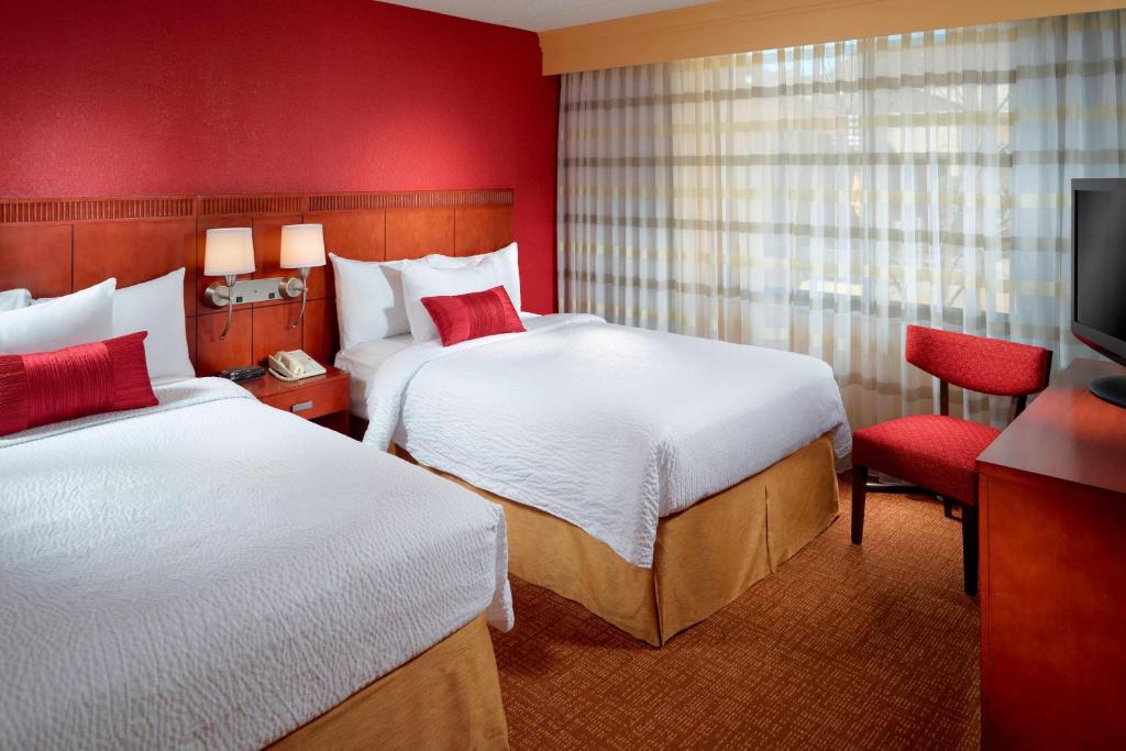 a hotel room with two beds and a television at Courtyard by Marriott Columbus in Columbus