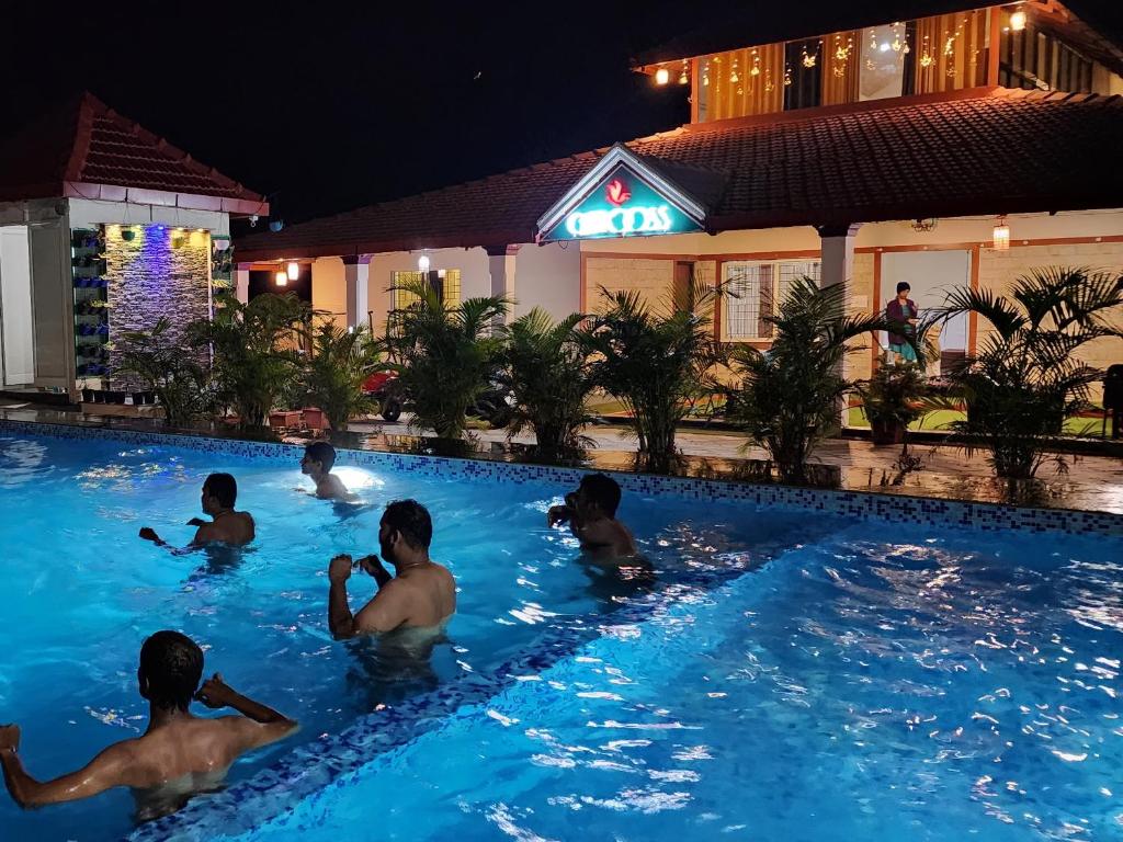 een groep mensen in een zwembad 's nachts bij Chirooss resort in Chikmagalūr