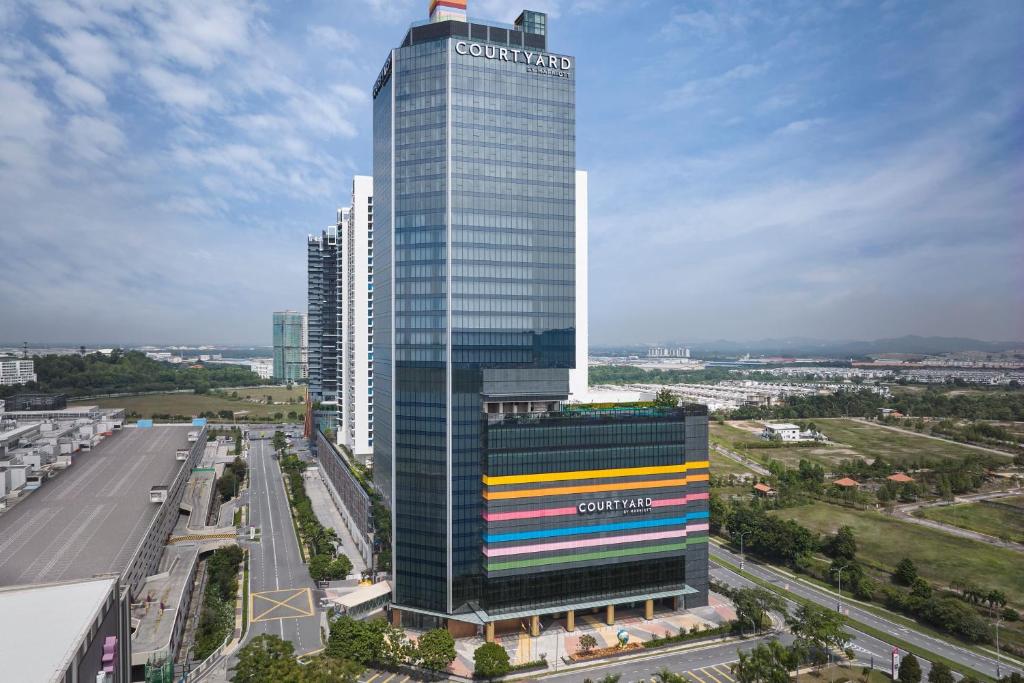 實地阿南的住宿－Courtyard by Marriott Setia Alam，一座高大的玻璃建筑,上面有一条色彩缤纷的条纹