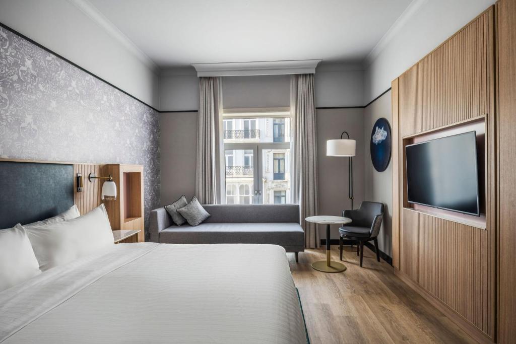 um quarto de hotel com uma cama e um sofá em Brussels Marriott Hotel Grand Place em Bruxelas