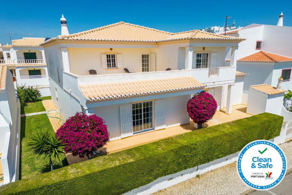 une grande maison blanche avec des fleurs roses devant dans l'établissement Casa do Topo Guesthouse, à Lagos