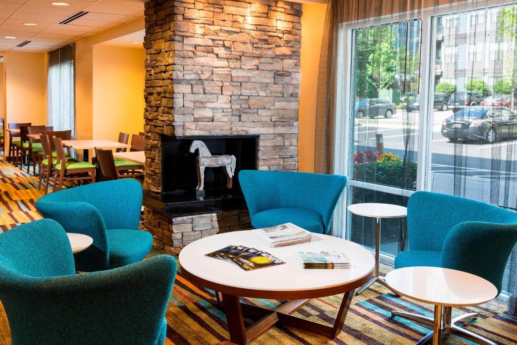 a waiting room with chairs and tables and a fireplace at Fairfield Inn & Suites by Marriott Atlanta Perimeter Center in Atlanta