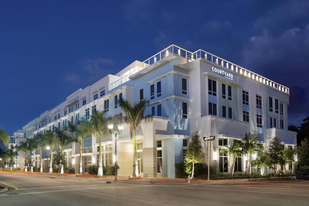 a white building with palm trees in front of it at Courtyard by Marriott Delray Beach in Delray Beach