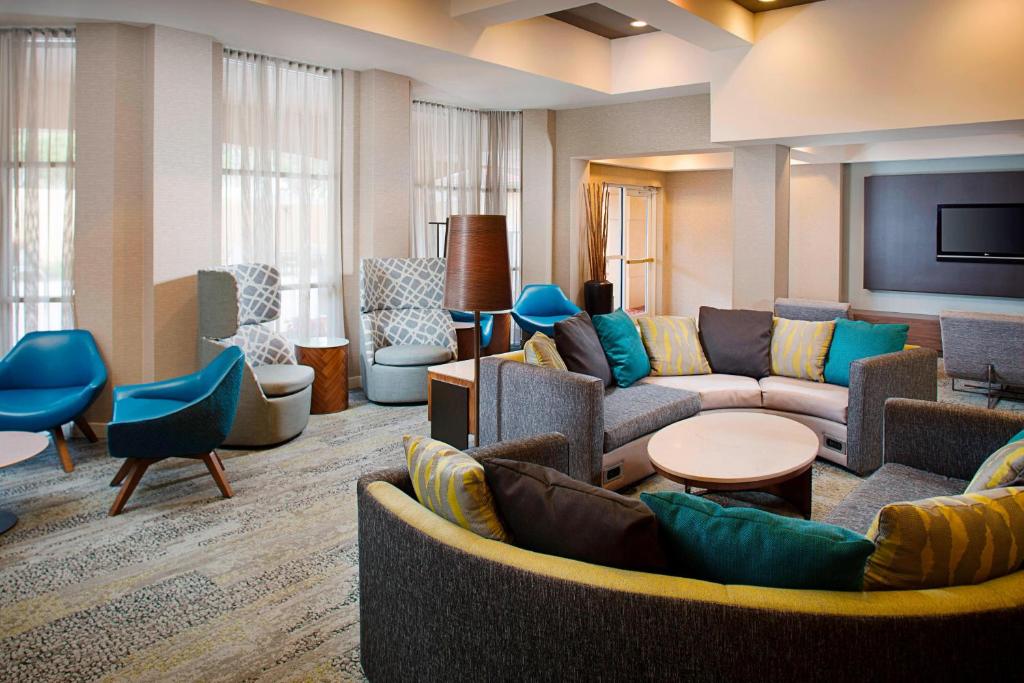 a living room with couches and chairs and a tv at Courtyard by Marriott West Palm Beach Airport in West Palm Beach