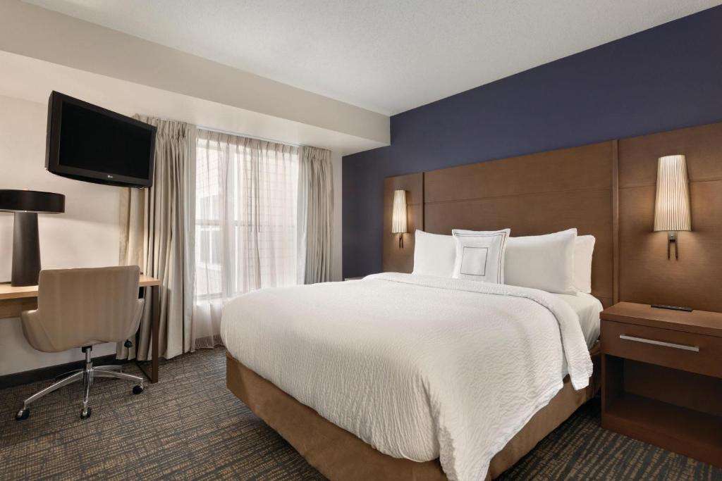 a hotel room with a large bed and a desk at Residence Inn by Marriott Buffalo Galleria Mall in Cheektowaga