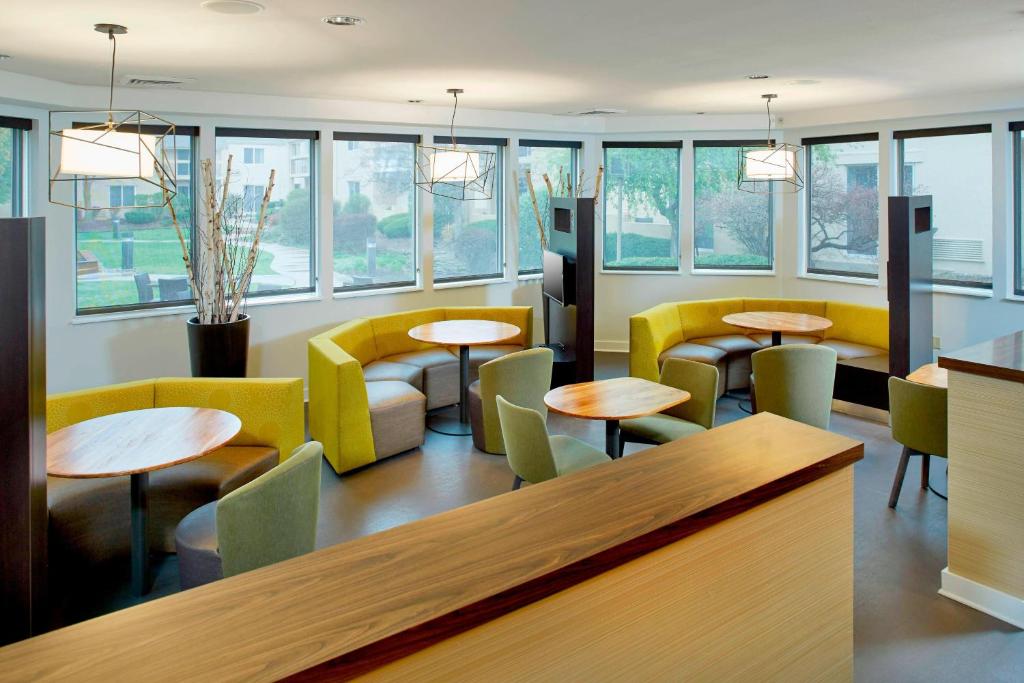 a restaurant with tables and chairs and windows at Courtyard by Marriott Lansing in Lansing