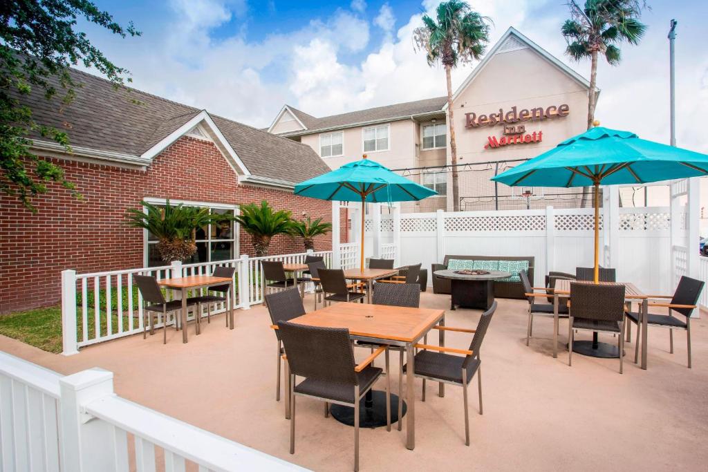 a patio with tables and chairs and umbrellas in front of a restaurant at Residence Inn Corpus Christi in Corpus Christi