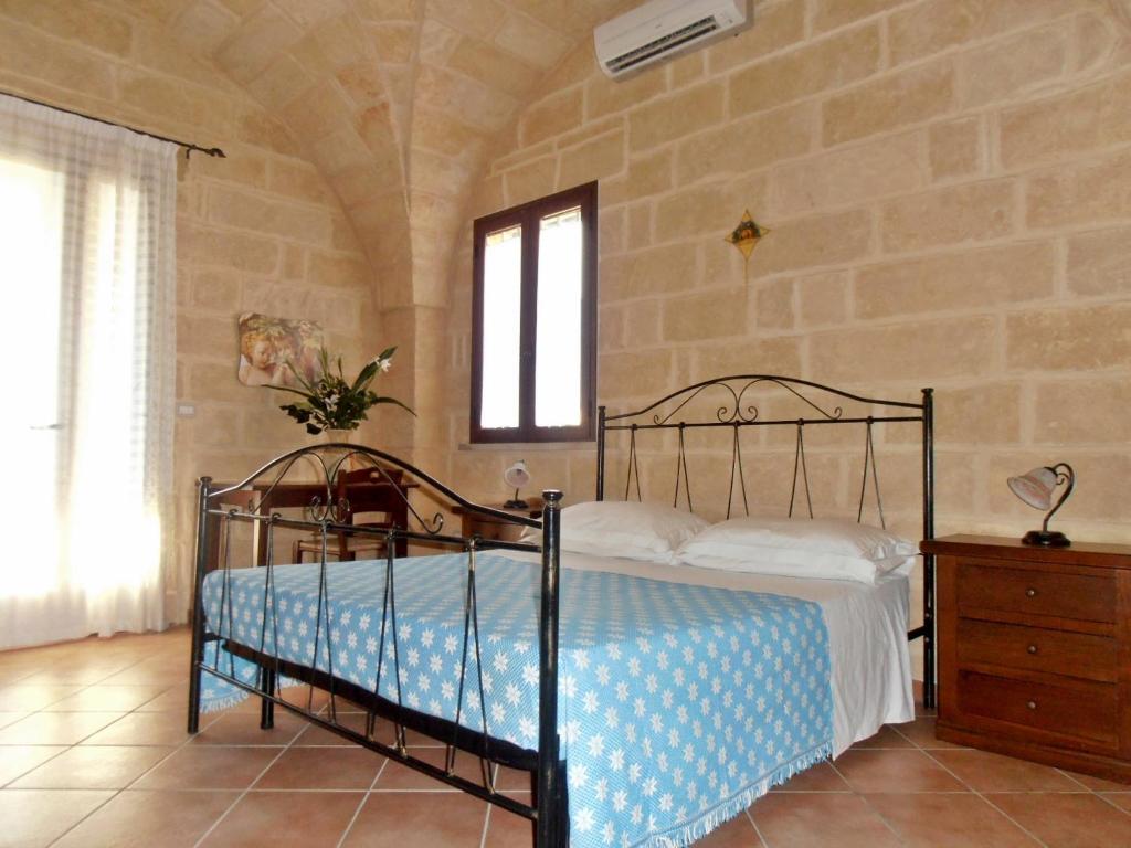 1 dormitorio con cama y pared de piedra en Il Corallo del Salento, en Vignacastrisi