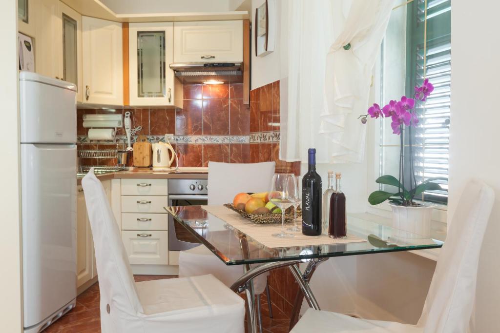 cocina con mesa de cristal y sillas blancas en Apartments Kalalarga Deluxe, en Makarska