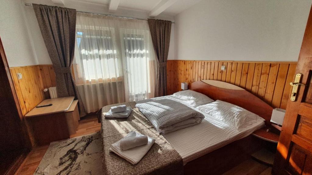 a bedroom with a bed with two towels on it at Pensiunea Paula in Moieciu de Sus