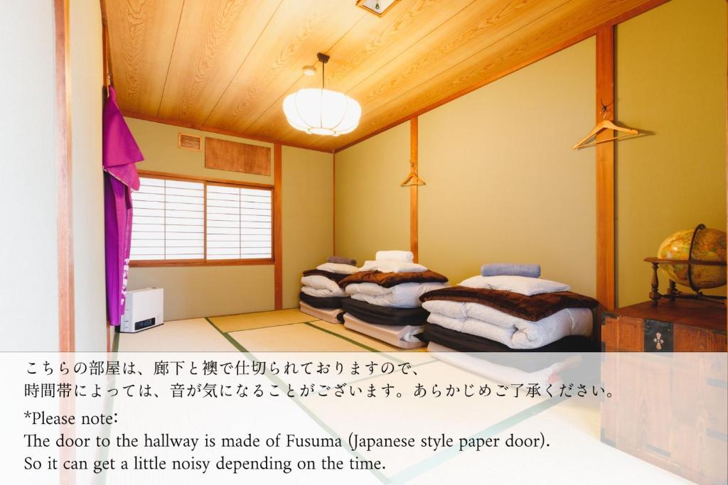 Couch Potato Hostel - Vacation STAY 88241 في ماتسوموتو: سريرين في غرفة مع كتابة على الحائط