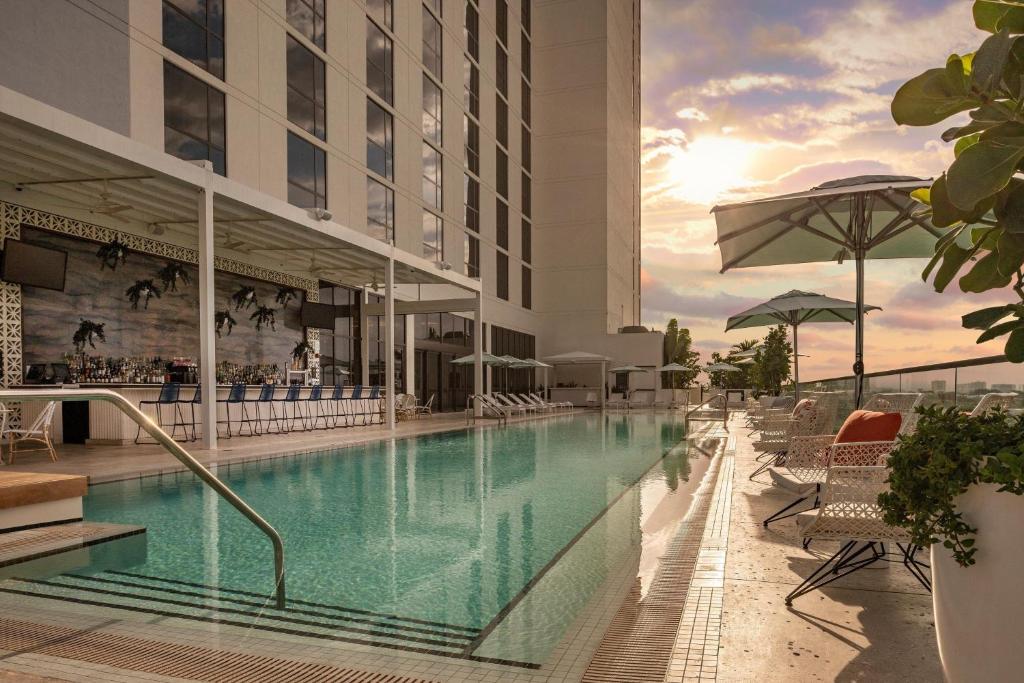 a swimming pool at a hotel with chairs and umbrellas at The Dalmar, Fort Lauderdale, a Tribute Portfolio Hotel in Fort Lauderdale