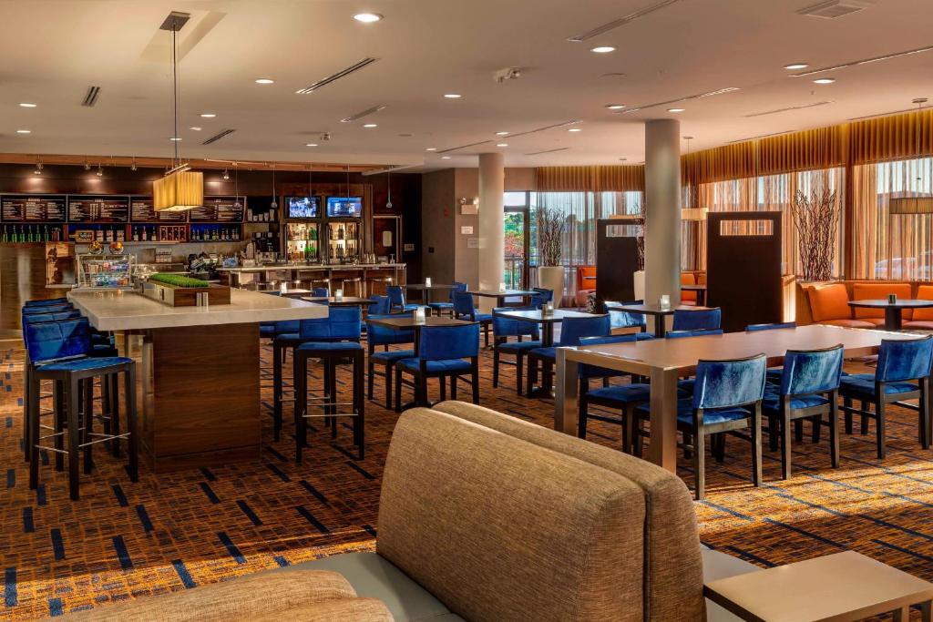 a restaurant with blue chairs and tables and a bar at Courtyard by Marriott Indianapolis Noblesville in Noblesville