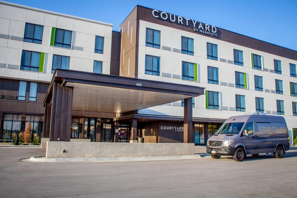 una furgoneta estacionada en un estacionamiento frente a un edificio en Courtyard by Marriott Omaha East/Council Bluffs, IA en Council Bluffs